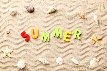 Fototapeta na wymiar Word Summer with seashells on beach sand