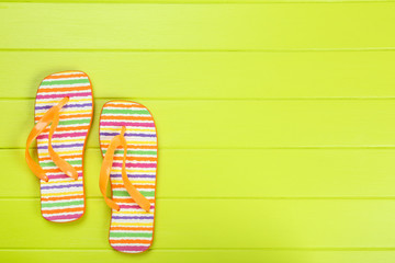 Pair of flip flops on green wooden table