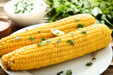 Fresh corn with parsley and butter on wooden table
