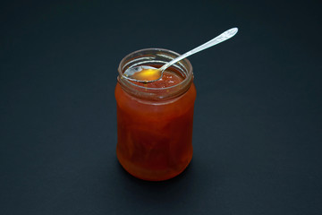 Glass jar of jam on a dark background