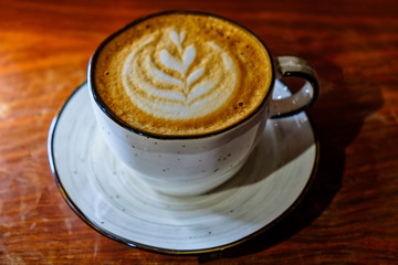 Coffee cuo with latte art on foamy top on tabletop