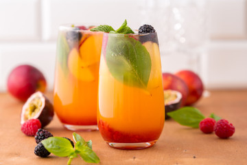 Summer cold peach cocktail or mocktail with basil, raspberry and blackberry