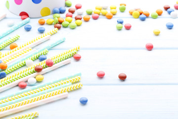 Colorful paper straws with candies on wooden table