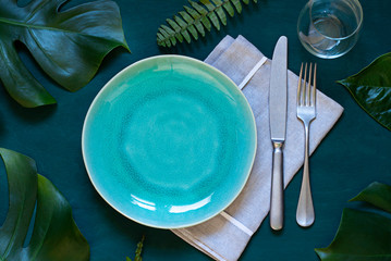 Summer table settings concept empty plate frame on the wooden dark background with tropical leaves....