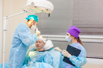The surgeon gives injections to the head. Baldness treatment. Hair transplant. Surgeons in the...