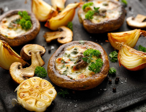 Baked Portobello Mushrooms Stuffed With Cheese And Herbs On A Black Background, Close-up. Vegetarian Food