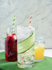 Delicious summer  lemonades with ice,berry, peach and lime on wooden background. Three glass with cold, fresh drink or coctail on green table