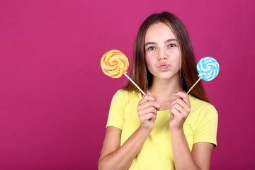 Young girl with lollipops on pink background