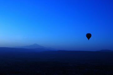 ballooning. A balloon flies in the sky in the rays of the rising sun. A bright sky, a haze, an extinct volcano on the horizon.