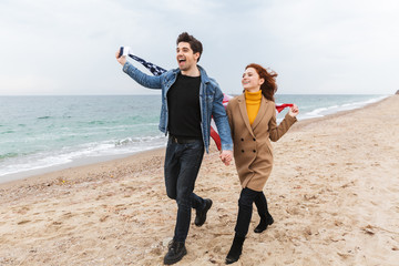 Cheerful young couple walking at the beach