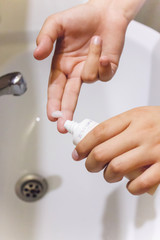 Hands of a young girl squeeze white cream on a finger over the sink