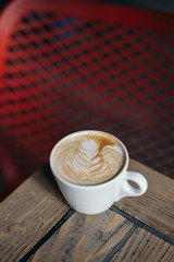 Coffee with latte art on wooden table and blurry background
