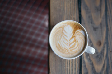 Coffee with latte art on wooden table and blurry background