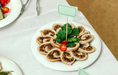 Baked turkey roll with prunes on a white plate.