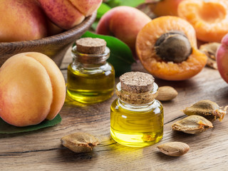Apricot kernel oil and apricot kernels on wooden background.