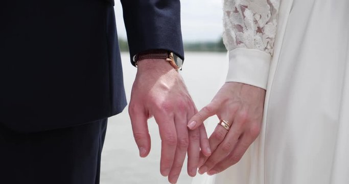 The groom holds the bride by the hand, hugs