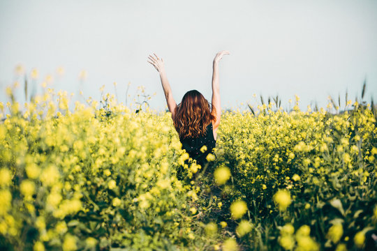 happiness nature summer vacation and people concept young woman dancing on poppy field from back