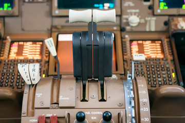 Engines thrust levers inside a big jet plane cockpit.