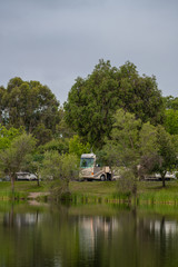 Fototapeta premium Rv Camping along the shore at Lake Camanche in the spring with reflection in water