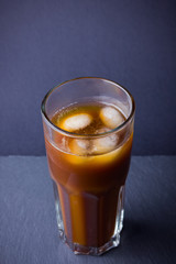 Iced coffee on a dark background. Summer drink with caffeine on the slate board. Iced coffee in a glass. Copy space