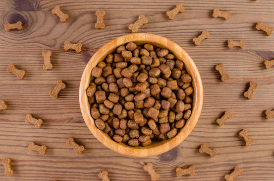 dog food in a bowl and snack like bones on wooden background, flat lay