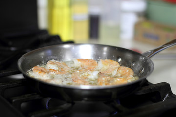 Shrimp scampi cooking in butter and garlic in a stainless steel skillet on the stove.