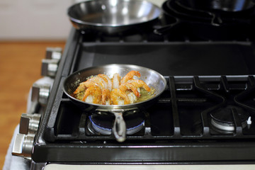 Shrimp scampi cooking in butter and garlic in a stainless steel skillet on the stove.