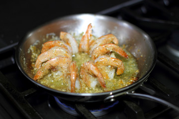 Fototapeta premium Shrimp scampi cooking in butter and garlic in a stainless steel skillet on the stove.
