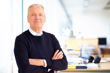 Fototapeta premium Elderly businessman portrait while standing with their arms crossed