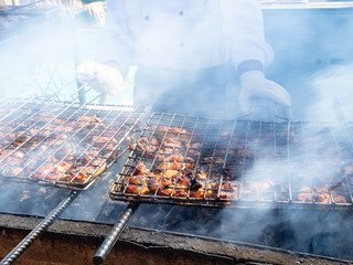 The Chef in white prepares meat on the barbecue.