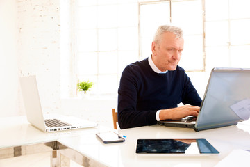 Executive elderly businessman working on laptop in the office