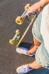 Top view of beautiful young woman holding skateboard