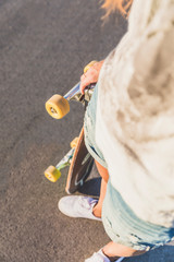 Beautiful young woman holding skateboard, top view