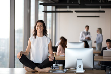 Happy female employee meditating at table in office
