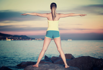 woman in sportwear doing exercises at  sunset sea shore