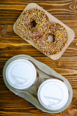 Paper cup for coffee, disposable ecological coffee supplies. Donuts on paper trays. Wooden table.Top view.