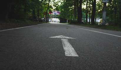 white arrow marked on the asphalt in the park, symbolizes the direction of movement