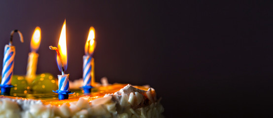 closeup of some unlit candles and just one lit candle after blowing out the cake