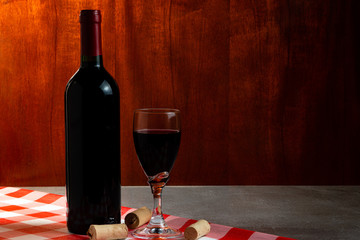Bottle of red wine in wine cellar for tasting. Red wood background. Wine tradition and culture...