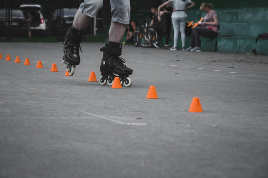 man skates on asphalt and goes round cones