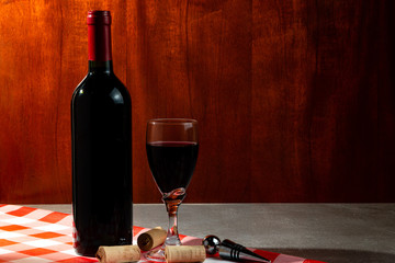 Bottle of red wine in wine cellar for tasting. Red wood background. Wine tradition and culture...