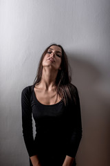 Dark mood portrait of a woman in front of a wall