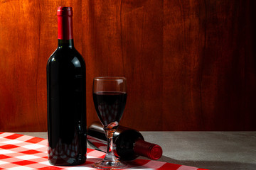 Bottle of red wine in wine cellar for tasting. Red wood background. Wine tradition and culture...