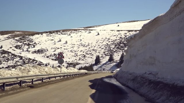 Car driving on narrow road in Beklemeto pass, Balkan mountains, Bulgaria. Melting snow in spring time, dangerous driving condition