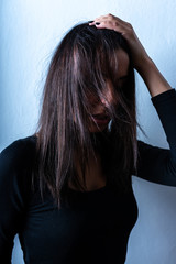 Fototapeta premium Dark mood portrait of a woman in front of a wall