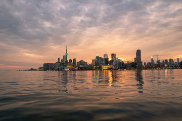 Obraz premium Toronto skyline reflecting in lake Ontario during a beautiful vibrant sunset. 