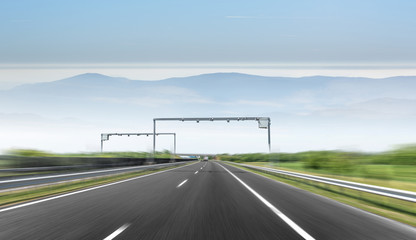 High-speed automobile highway on the background of mountains and a bridge over the road.