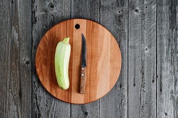 Fresh zucchini on the background of a cutting board. View from above. Old textured wooden board.