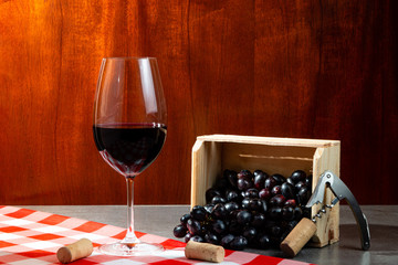 Bottle of red wine in wine cellar for tasting. Red wooden background with wooden box with grapes....