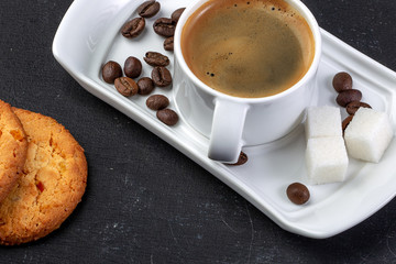 white cup of fresh hot coffee, grains of coffee and sugar cubes
